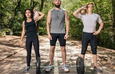 Three adults exercising outdoors with weights, promoting fitness and diversity.
