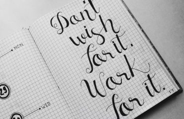Close-up of motivational calligraphy on grid paper, inspiring message for productivity.